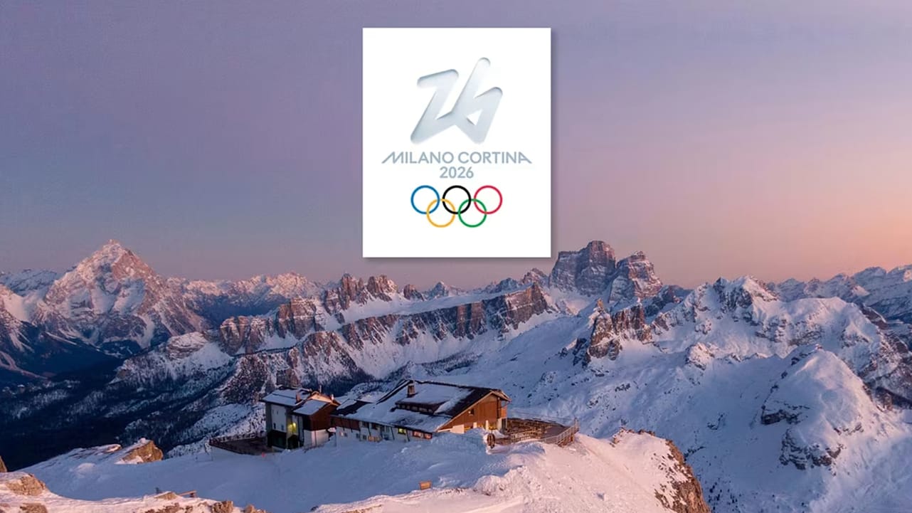 Gün batımında karla kaplı Dolomit dağları ve zirvedeki bir dağ evi; ortada beyaz kutu içinde "Milano Cortina 2026" logosu ve Olimpiyat halkaları.